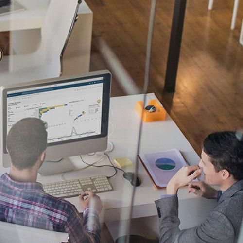 Two employees looking at a Tableau dashboard on a computer monitor in their office