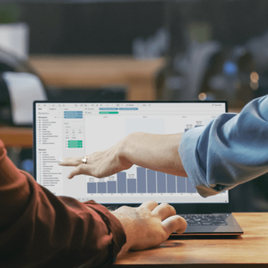 Two colleagues analyze data together on a lap top at their office